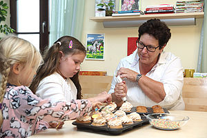 Haushälterin dekoriert Muffins mit einem Kind