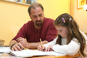 Betreuer macht mit einem Mädchen die Hausaufgaben