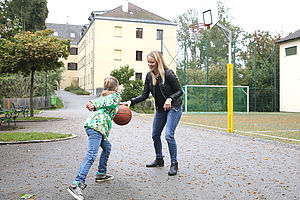 Betreuerin spielt Basketball mit einem Mädchen
